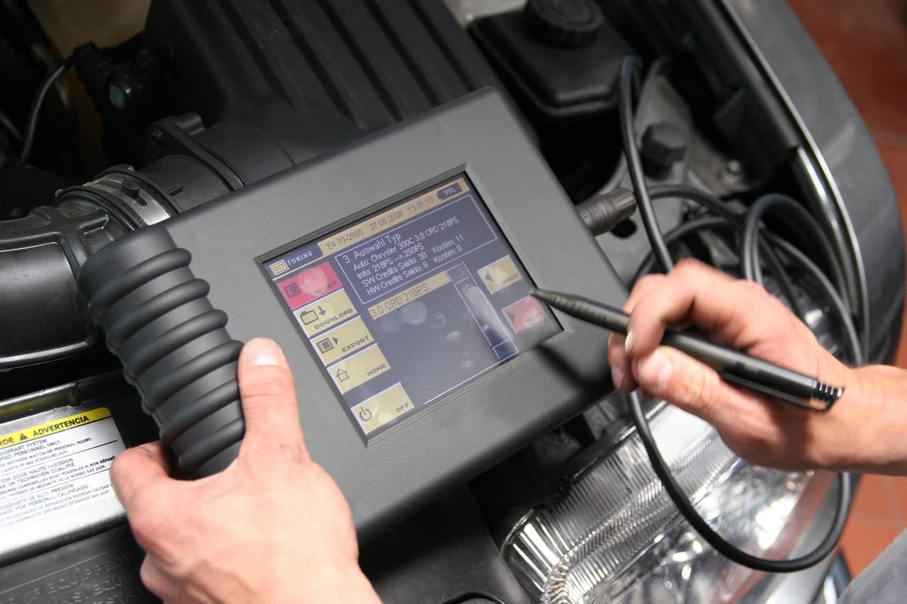 A diagnostic tester plugged in under a car bonnet, reading fault codes